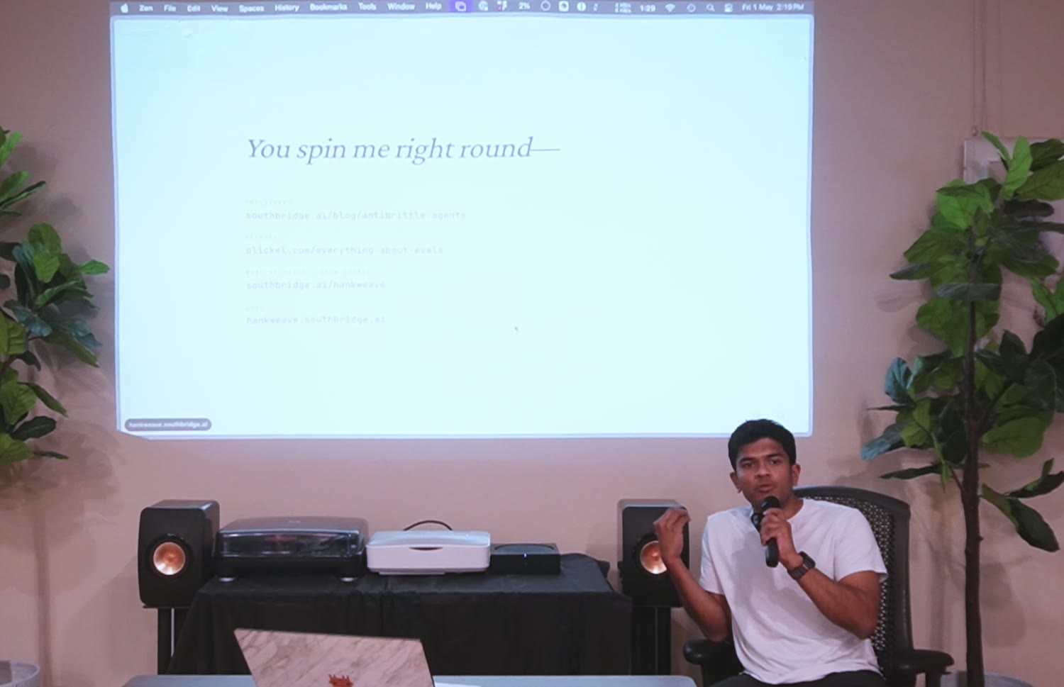 During the Q&A, seated and mid-answer, the "You spin me right round" links slide projected behind.
